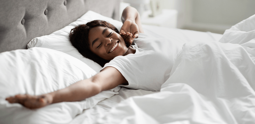 woman laying in a bed with white linens 