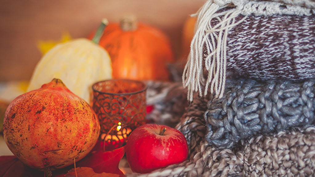 A lighted candle, some fruits, vegetables and blankets.