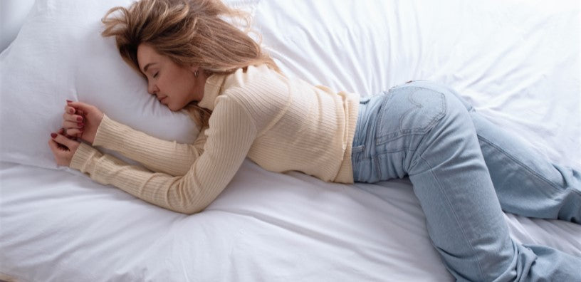 A woman peacefully sleeping on a bed, her arms outstretched comfortably beside her.