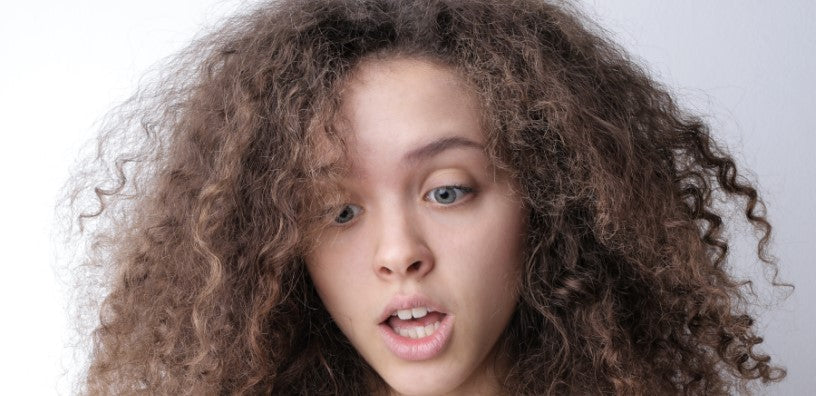 A woman with curly hair looks surprised.