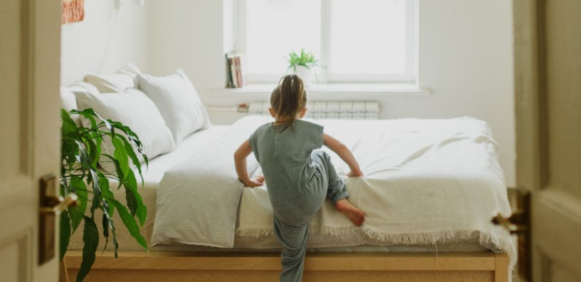 A kid is climbing up the bed.