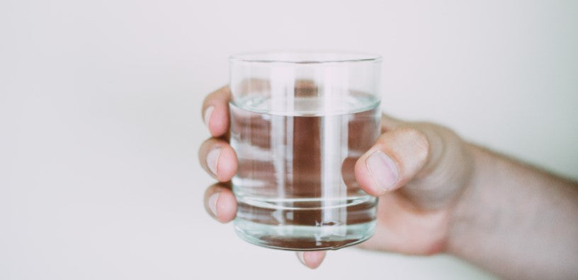 A hand holding a glass of water.