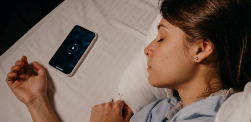 A woman is sleeping with her mobile phone beside her.