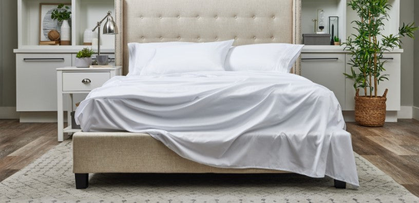 A stylish bed adorned with sheets and fluffy pillows, perfect for a restful night's sleep.