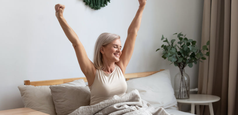 Happy woman stretching in bed after a good night's sleep, feeling refreshed and energized.