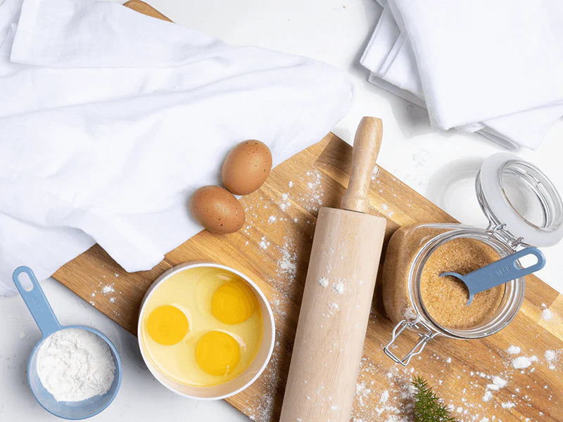 A cutting board with various baking tools and ingredients, for a delicious baking session.