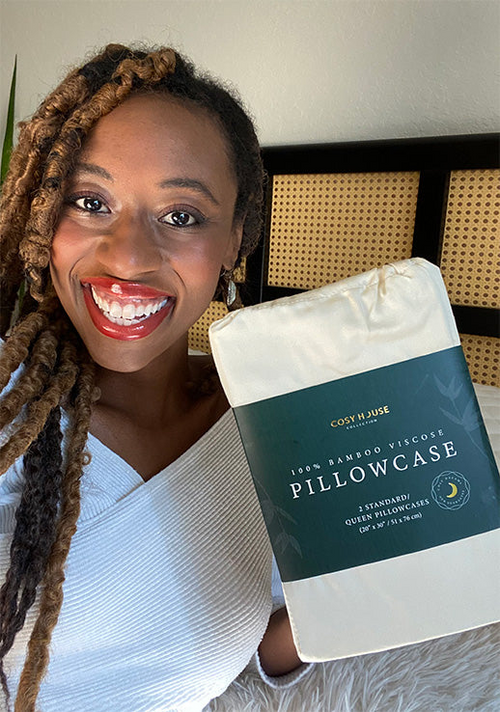 A smiling customer flexing a packaged pair of 100% Bamboo pillowcases.