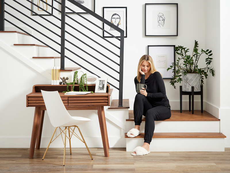 A woman using her loungewear set is casually sitting on the stairs, enjoying a moment of relaxation.