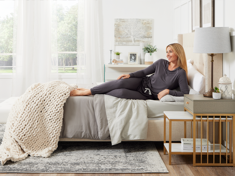 A woman relaxes on a bed in a stylish bedroom, enjoying a moment of peace in her personal space.