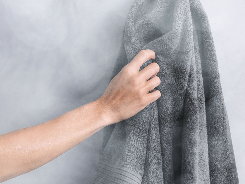 A person holds a steaming towel, ready to refresh and relax after a long day.