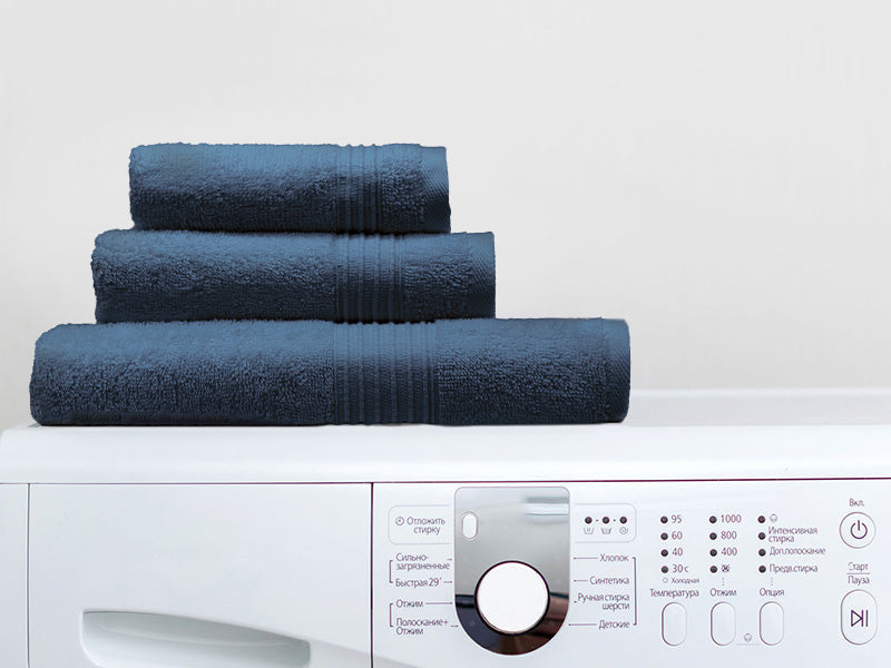 A folded set of Cosy House Collection’s Essential Cotton Towel set on top of a washing machine.