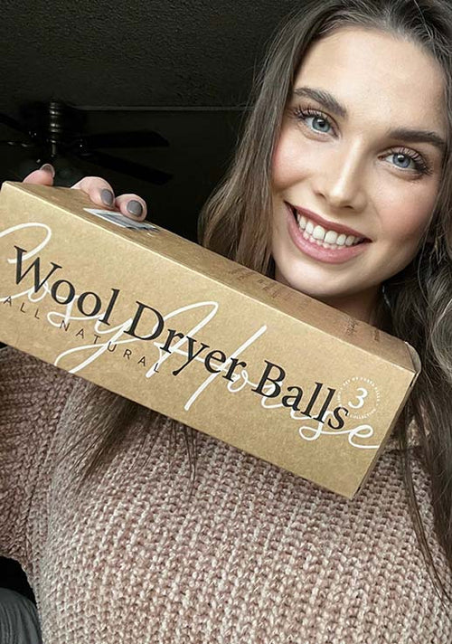 A satisfied customer flexing her packaged Cosy House Collection All Natural Wool Dryer Balls..