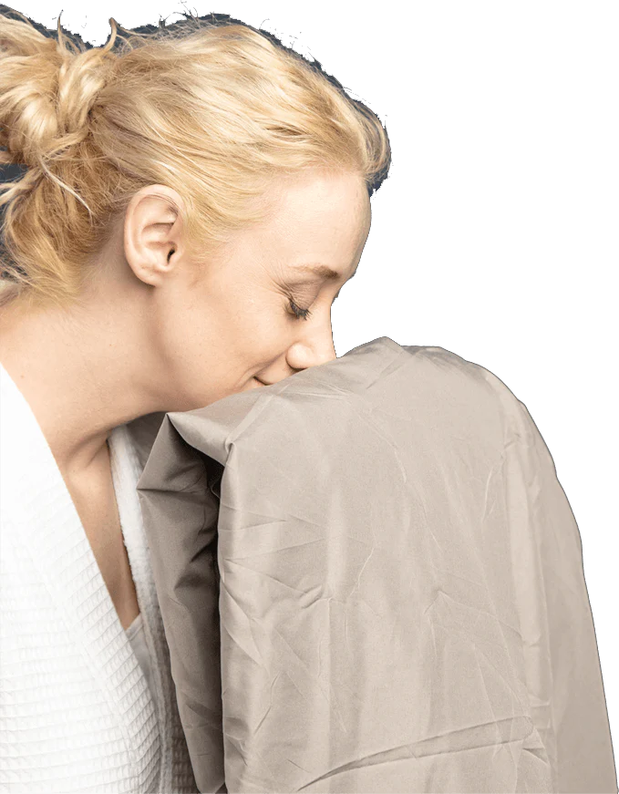 A woman feeling and smelling a Cosy House Collection sheet.